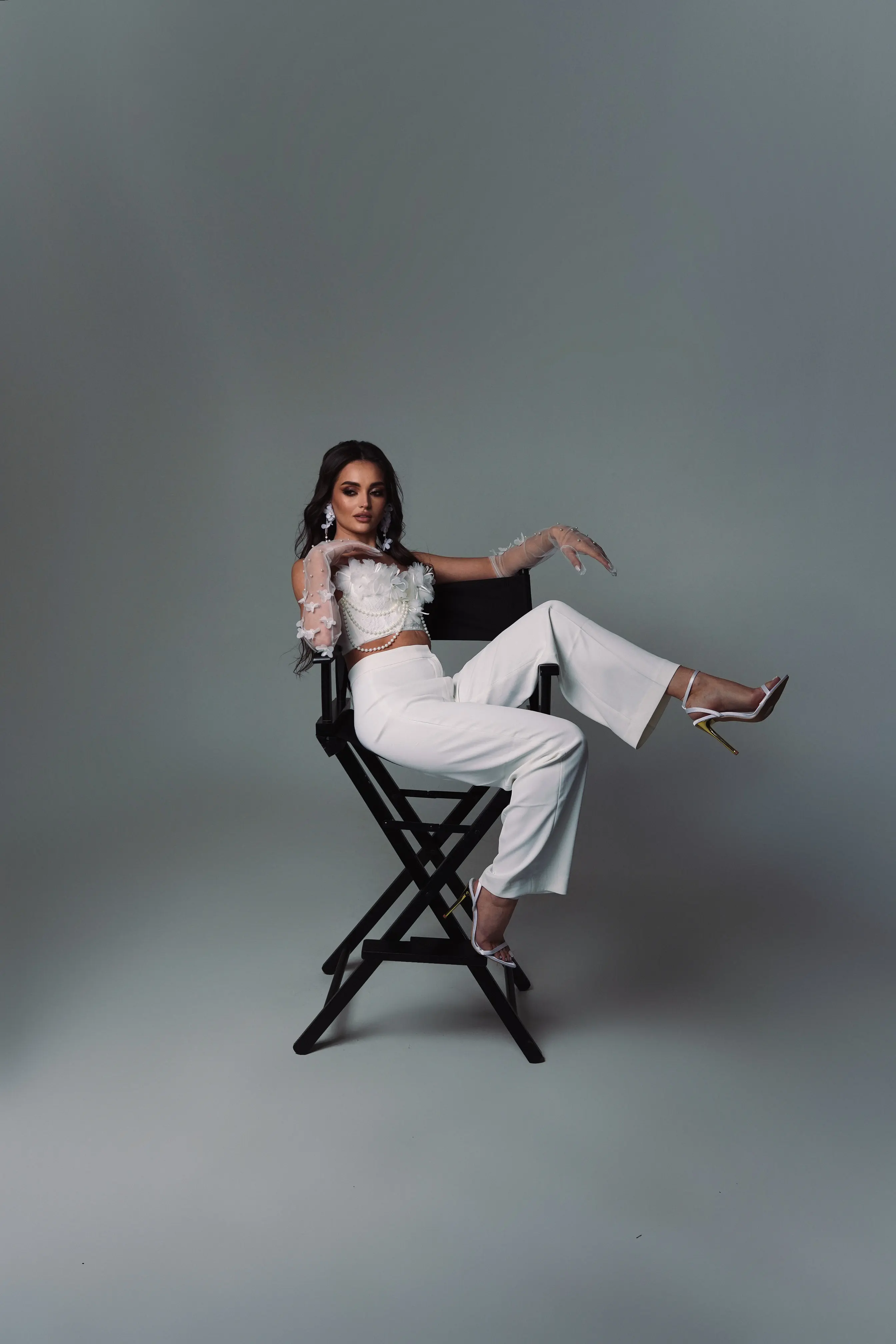 Director's chair power pose — tailored whites, controlled shadow